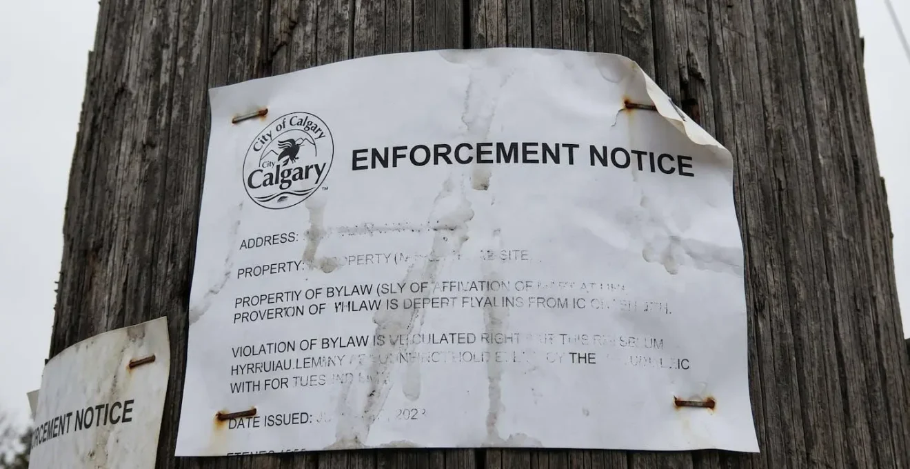 Extreme close-up macro photograph of an official City of Calgary bylaw enforcement notice document with crisp paper texture and shallow depth of field, background blurred